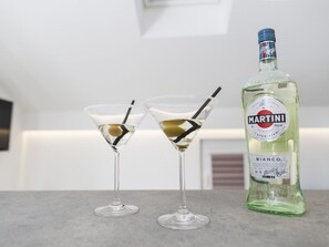 Two martini glasses with olives and straws on a countertop next to a bottle of Martini Bianco.
