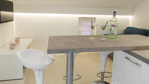 A modern kitchen with a bar area, white bar stools, a white sink, and a bottle of Martini Bianco on the counter. - Apartment in Imotski Near Blue Lake (Imotski)