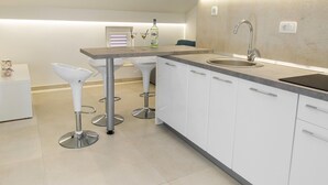 A modern kitchen with white cabinets, a stainless steel sink, and bar stools. - Apartment in Imotski Near Blue Lake (Imotski)