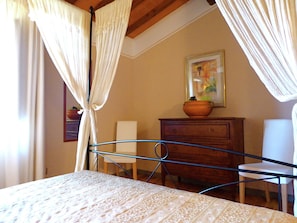 A bedroom with a bed, a dresser, a chair, and a painting on the wall. - Holiday Home in Montecarelli With Pool (Barberino di Mugello)