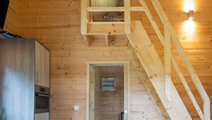 A wooden interior with a staircase leading to an upper level, a kitchen area with built-in appliances, and a visible electrical panel. - Secluded Chalet in Rogery (Gouvy)