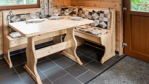 A wooden interior with a table and benches, a window with a view of greenery, and a door. - Secluded Chalet in Rogery (Gouvy)