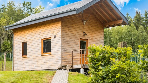 A wooden cabin with a sloped roof, a small porch, and a pathway leading to the entrance. - Secluded Chalet in Rogery (Gouvy)