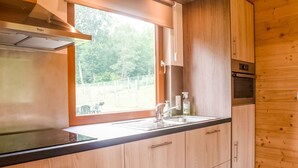 A modern kitchen with a built-in stove, a sink, and wooden cabinetry. - Secluded Chalet in Rogery (Gouvy)