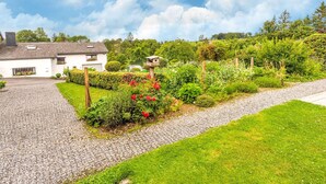A white house with a gravel driveway and a garden with various plants and flowers. - Quaint Holiday Home in Trois-Ponts near Forest (Trois-Ponts)