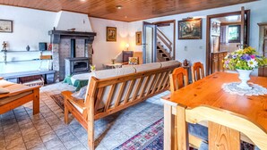 A cozy room with a wooden ceiling, a fireplace, a dining table with chairs, and a staircase leading to another level. - Quaint Holiday Home in Trois-Ponts near Forest (Trois-Ponts)