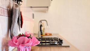 A kitchen with a pink flower vase on the counter, a stove, and a hanging pot rack. - Comfortable Holiday Home in Pistoia With Pool (Pistoia)