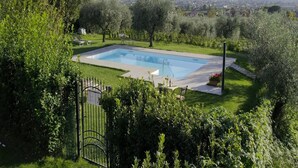 A rectangular swimming pool surrounded by lush greenery and a metal gate. - Comfortable Holiday Home in Pistoia With Pool (Pistoia)