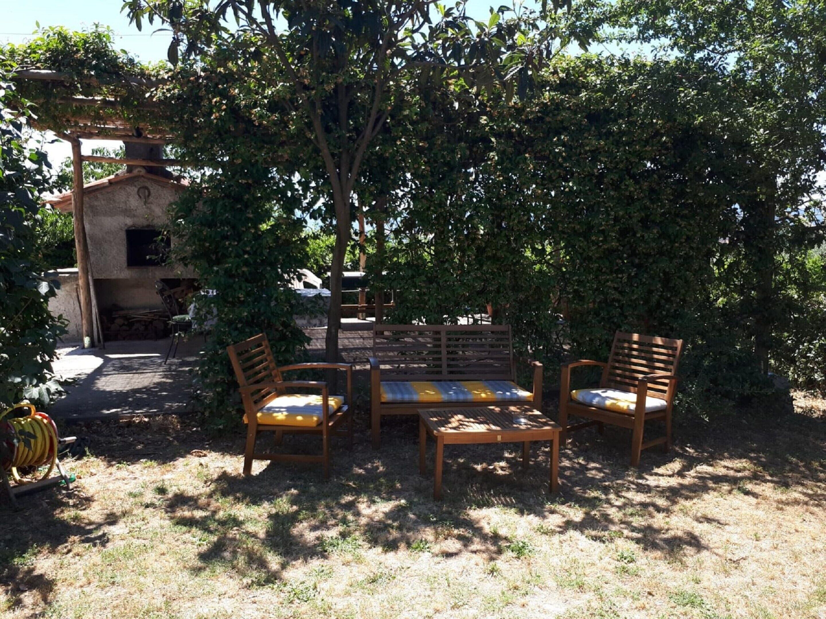 A patio with wooden furniture, a fire pit, and a stone wall.