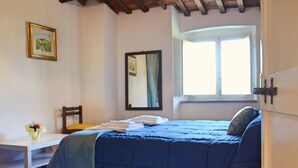 A bedroom with a bed, a chair, a small table, a window, and a mirror. - Comfortable Holiday Home in Pistoia With Pool (Pistoia)
