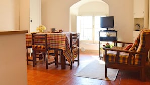 A dining area with a table set for two, a television on a stand, and a sofa in the background. - Comfortable Holiday Home in Pistoia With Pool (Pistoia)