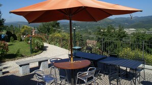 An outdoor patio with a table and chairs, an umbrella, and a view of the surrounding landscape. - Holiday Home in Montecarelli With Pool (Barberino di Mugello)