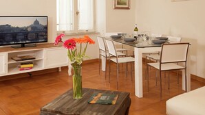 A modern living room with a television, a dining table set for four, and a coffee table with books. - Apartment near Piazza del Popolo & Villa Borghese (Rome)