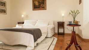 A neatly arranged bedroom with a bed, bedside tables, and a small table with a lamp and decorative items. - Apartment near Piazza del Popolo & Villa Borghese (Rome)