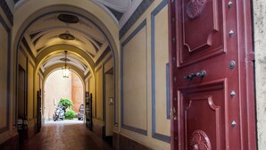 A corridor with a red door, arched ceiling, and a view into a room with a motorcycle. - Apartment near Piazza del Popolo & Villa Borghese (Rome)