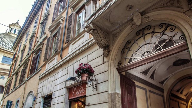 A historic building with ornate architectural details, including a decorative iron gate and a shop entrance with mannequins displaying clothing. - Apartment near Piazza del Popolo & Villa Borghese (Rome)
