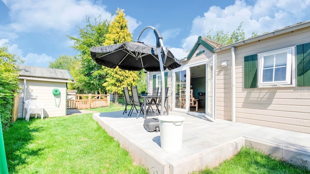A patio area with a table and chairs, a trash can, and a covered seating area. - Chalet in Stegeren Near Hiking Trails (Stegeren)