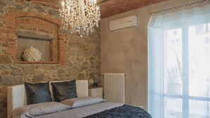 Un dormitorio con pared de piedra, una araña, un radiador y una ventana con vistas.