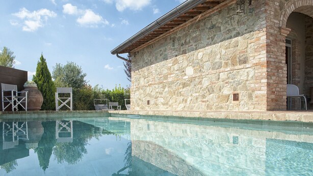 Una piscina cristalina con paredes de piedra y una estructura de techo de madera.