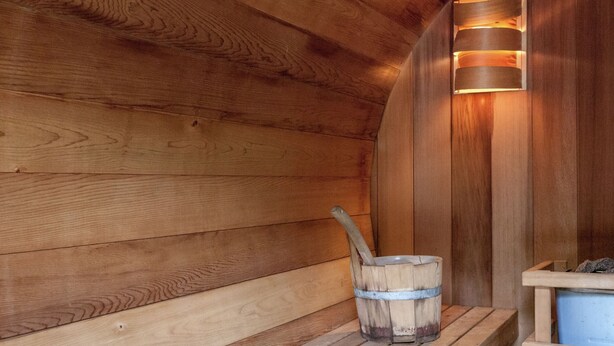 A wooden sauna with benches and a bucket.