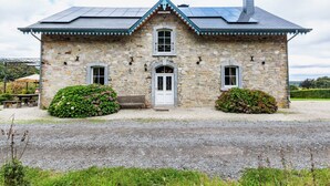 A stone building with a gabled roof, a central entrance, and two side windows.