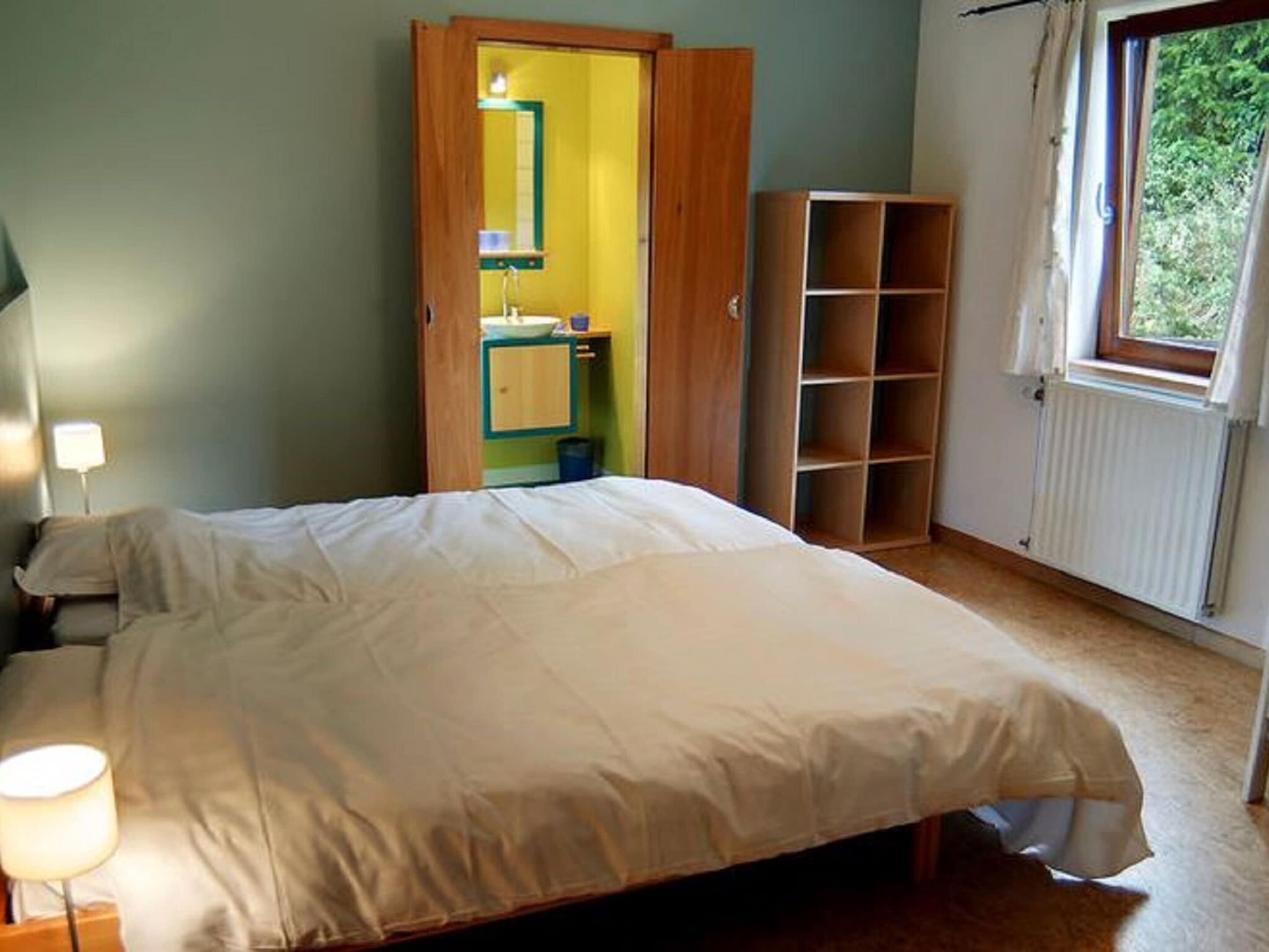 A bedroom with a bed, a nightstand, a wardrobe, a radiator, and a window.