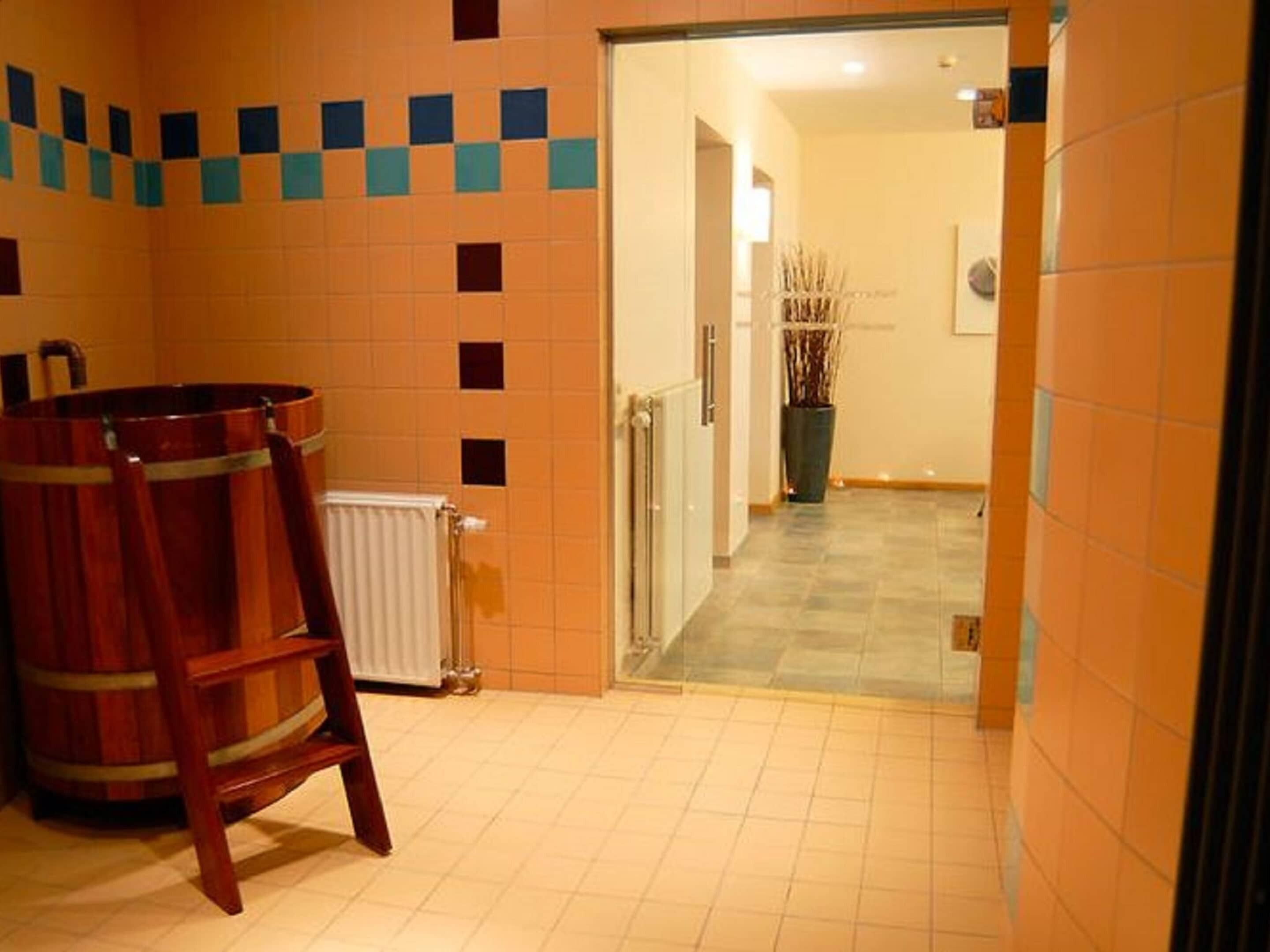 Ein Zimmer mit einem Holzfass, einem Heizkörper und einem Fliesenboden.