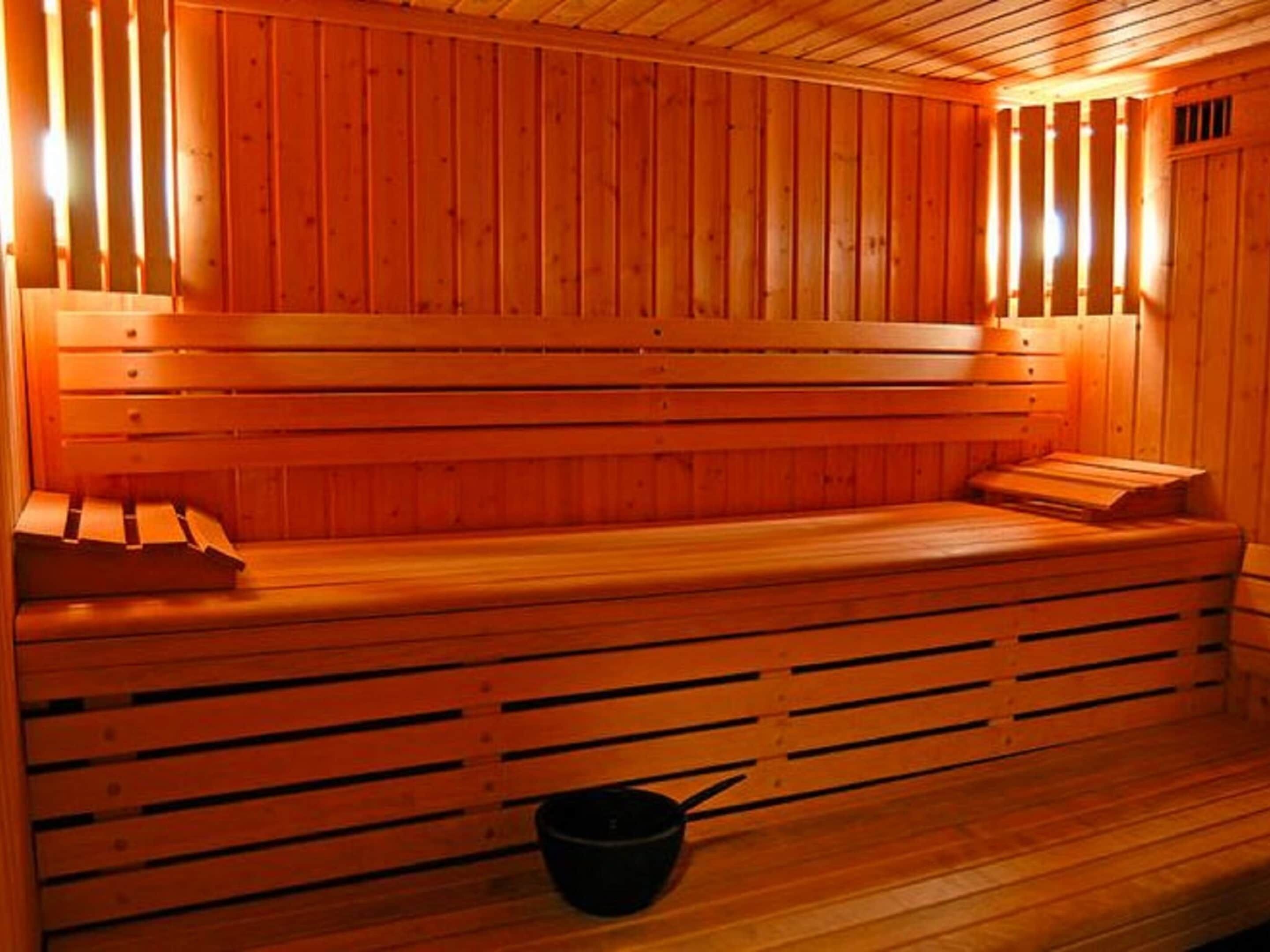 A wooden sauna with benches and a bucket.