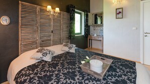 A bedroom with a bed, wooden shutters, a dresser, and a mirror.