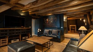 Un accogliente soggiorno con un grande televisore, divani in pelle, un tavolino in legno e un quadro appeso al muro.