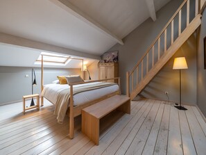 Relax in a serene bedroom with a sloped ceiling, wooden bed frame, and cozy reading nook.