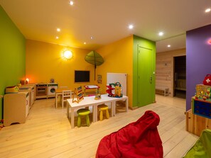 Une salle de jeux aux couleurs vives, avec une table, des chaises et des jouets pour enfants.