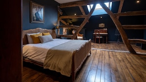 Una camera da letto con soffitto in legno, un letto, una scrivania e una sedia.