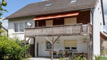 A two-story house with a balcony, a satellite dish, and a covered patio area.