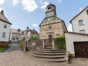 A traditional half-timbered building with a stone facade, a wooden door, and a small circular window. - Wohnung in Fuldabruck am Naturpark (Fuldabruck)