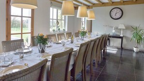A dining area with a long table set for a meal, wooden beams on the ceiling, and large windows allowing natural light. - Diksmuide Mansion With Games (Diksmuide)