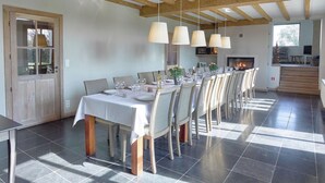 A dining area with a long table set for six, wooden beams on the ceiling, and a fireplace in the background. - Diksmuide Mansion With Games (Diksmuide)