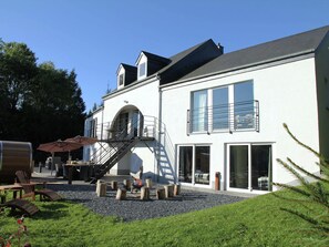 Ein zweigeschossiges Gebäude mit Balkon, Außenbereich zum Sitzen und einer Feuerstelle.