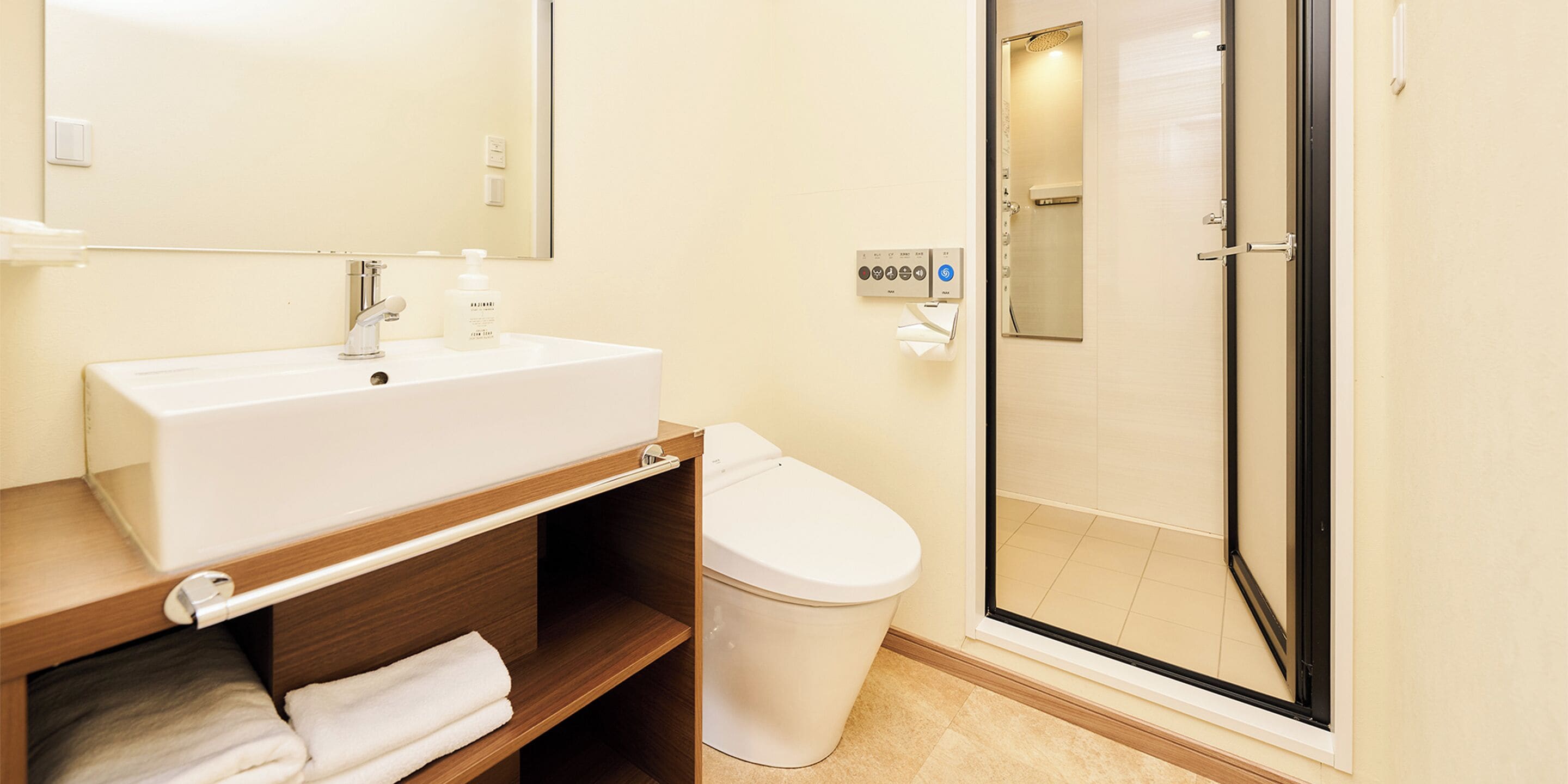 A bathroom with a white sink, a mirror, a toilet, and a glass shower enclosure.