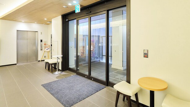 A modern hotel lobby with a reception desk, a seating area with two chairs, a small table, and a large glass door leading to a balcony. - Rakuten STAY URBAN Shijo Teramachi (Kyoto)