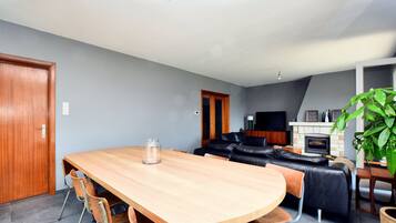 A modern living room with a wooden dining table, black leather sofa, and a fireplace.