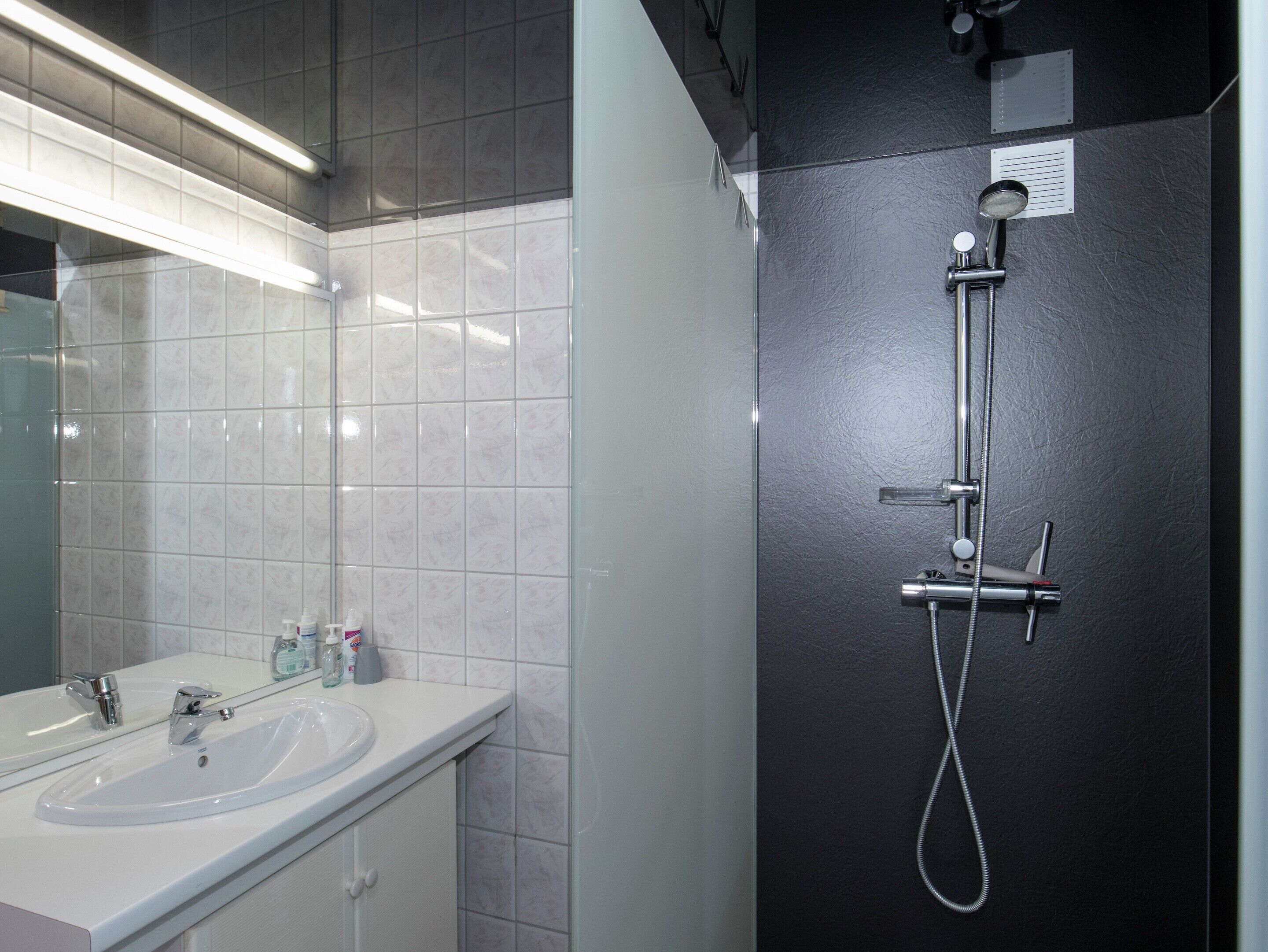 Ein modernes Badezimmer mit Waschbecken, Spiegel und Dusche mit Duschbrause.