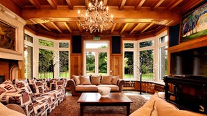 A spacious room with a large sofa set, a piano, and a chandelier. - Magnificent Luxury Chateau in Vast Garden with Sauna & Hot Tubs (Chiny)