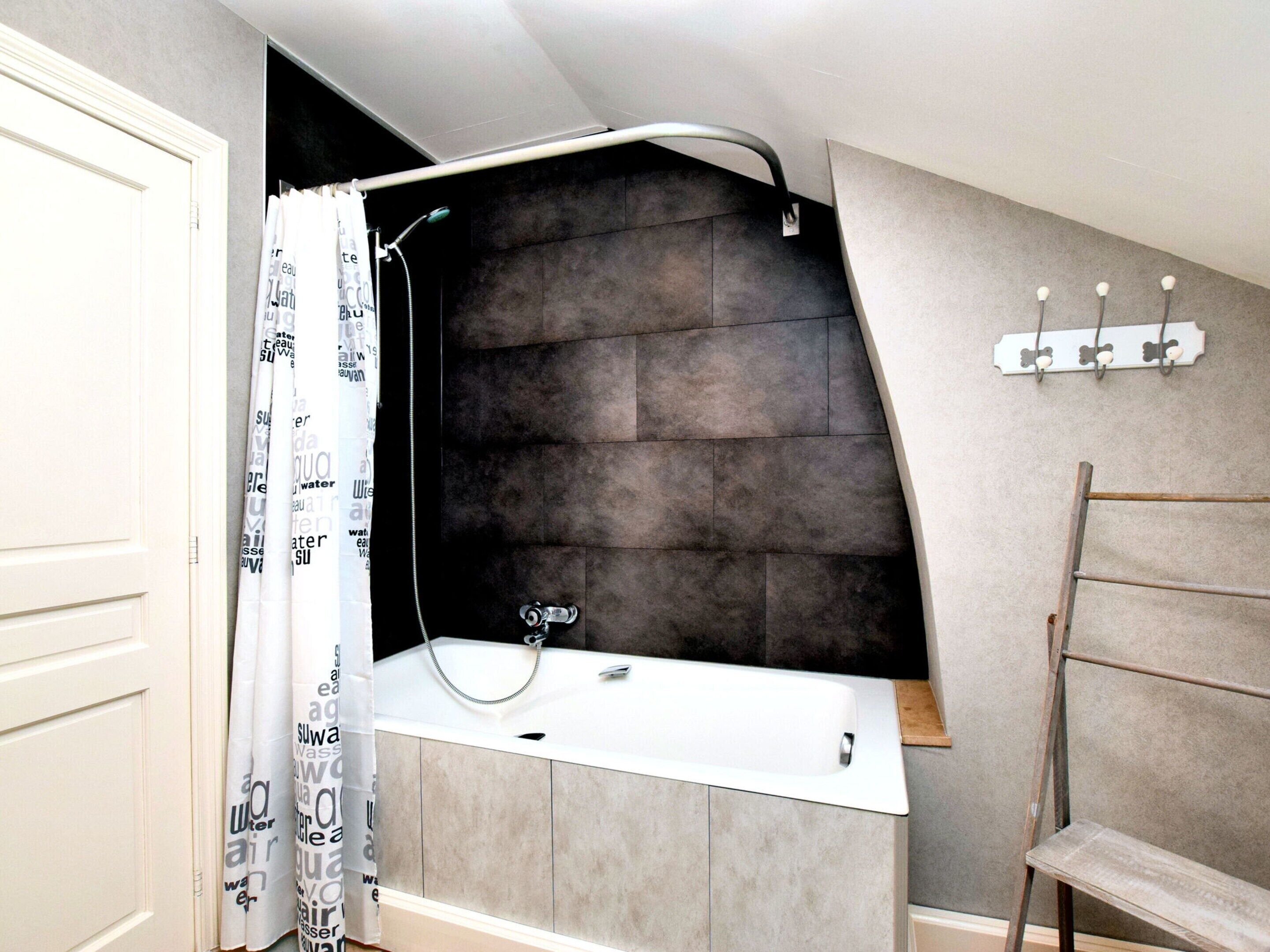 A bathroom with a shower, a sink, and a towel rack.