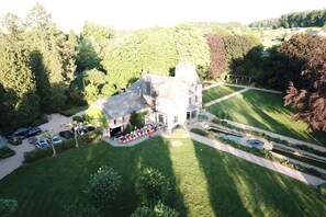 Une vue aérienne d’un grand bâtiment historique doté d’une vaste pelouse, d’une piscine et d’un jardin bien entretenu.