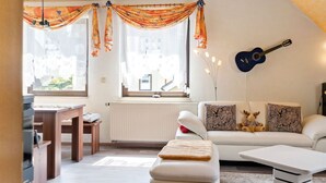 A modern living room with a white sofa, a coffee table, and a dining area with a wooden table and chairs.