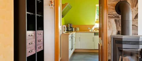 A modern kitchen with a green wall, a stone fireplace, and a wooden cabinet with drawers.