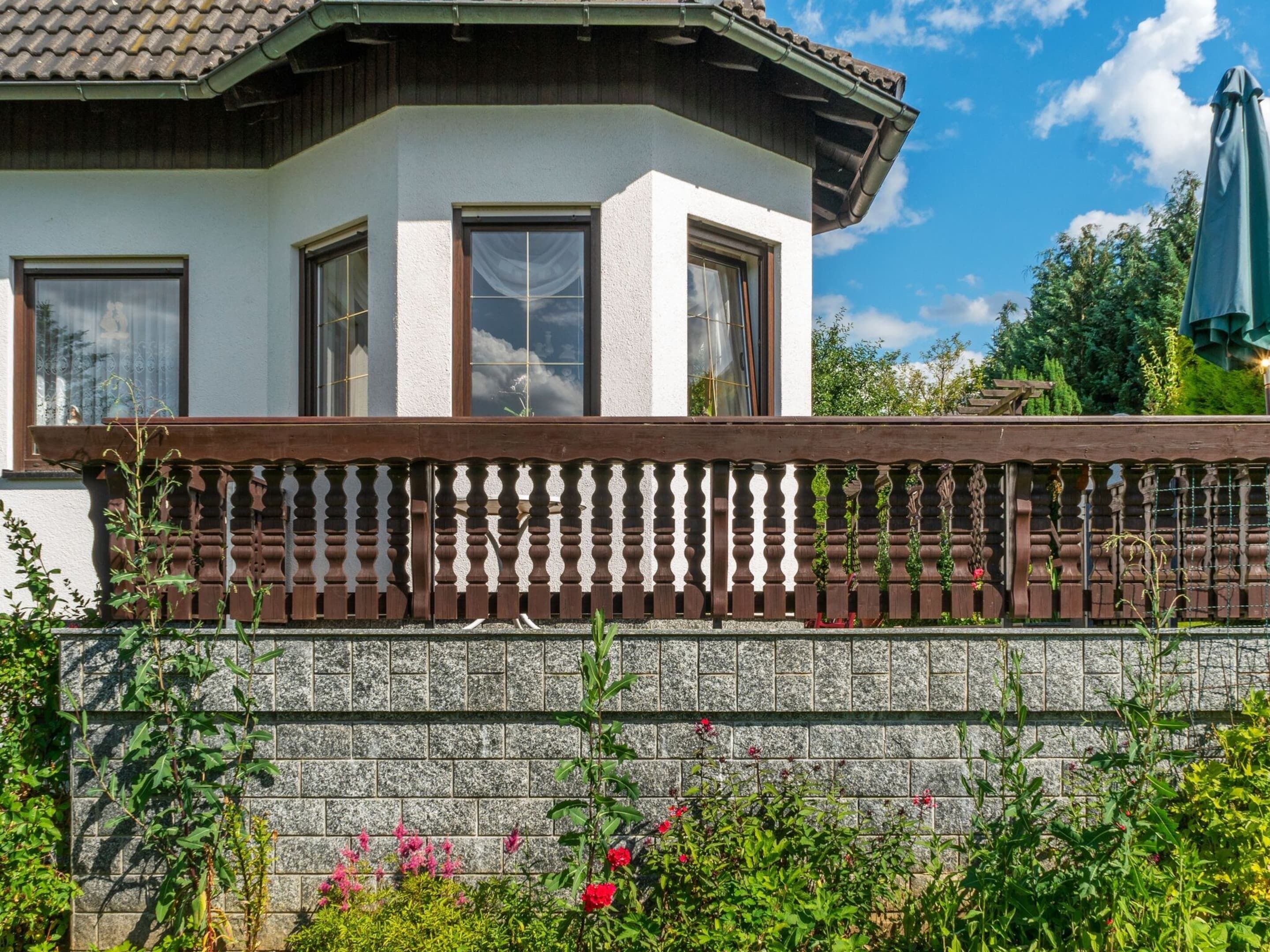 A corner building with a stone wall, wooden balcony railing, and a tiled roof.