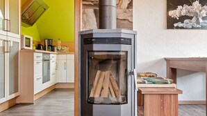 A modern kitchen with a wood-burning stove, white cabinets, and a dining area with a table and chairs.