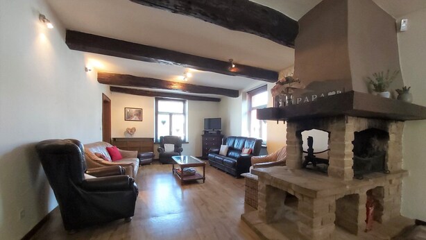 A living room with a stone fireplace, leather sofas, a television, and a wooden floor. - Pleasant Holiday Home in Herbeumont near Semois River (Herbeumont)